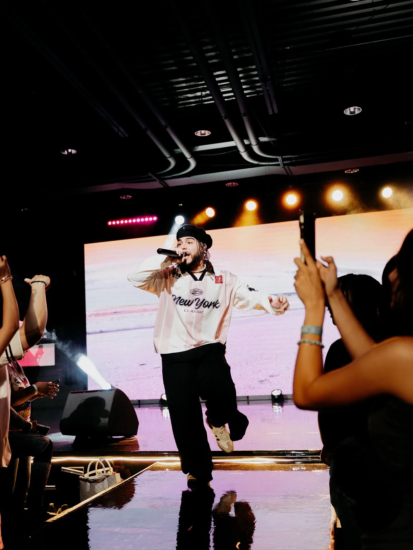 Kenny Rivers performing on stage surrounded by a live crowd and colorful lights